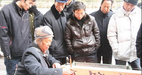 街頭潑墨書(shū)法變錢(qián) 貼春聯(lián)討吉慶汽車(chē)也來(lái)湊熱鬧