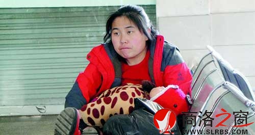 候車廳里，一位母親抱著睡著的孩子發(fā)呆