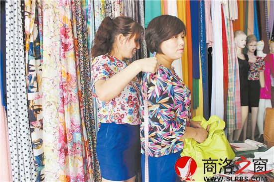 雷小莉仔細(xì)地為客人量尺寸，量體裁衣是裁縫鋪?zhàn)畲蟮膬?yōu)勢。