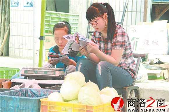 商州區(qū)楊斜鎮(zhèn)集市上，南思佳和妹妹在幫父母賣菜，閑暇之余，她們會拿起課外讀物翻一翻。在這個假期里，她們呆的最多的地方就是這個菜攤。